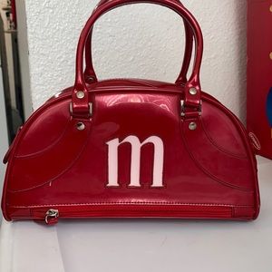 Red bag has a M logo on the front has 2 zippers to put things in inside